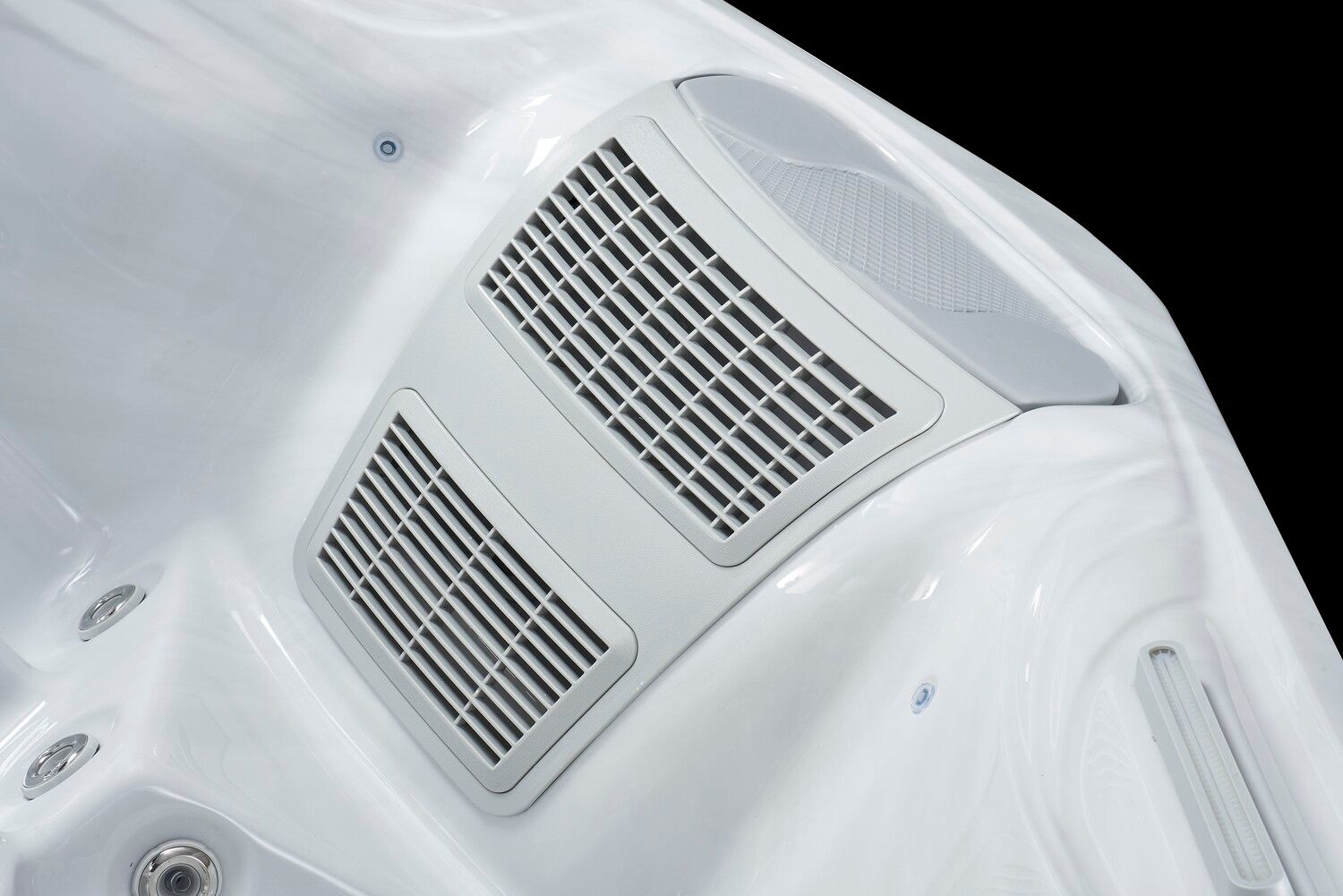 Close-up of a white hot tub interior. Features two rectangular ventilation grills and smooth, curved surfaces.