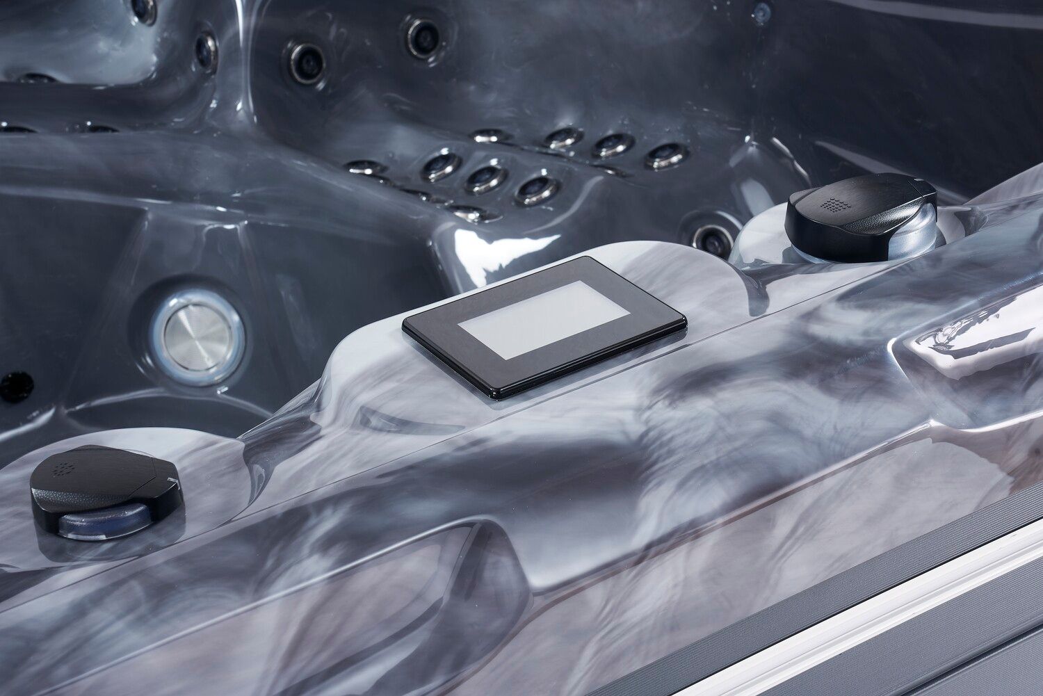 Close-up of a hot tub interior with a control panel and jets. Gray and blue swirls of plastic.