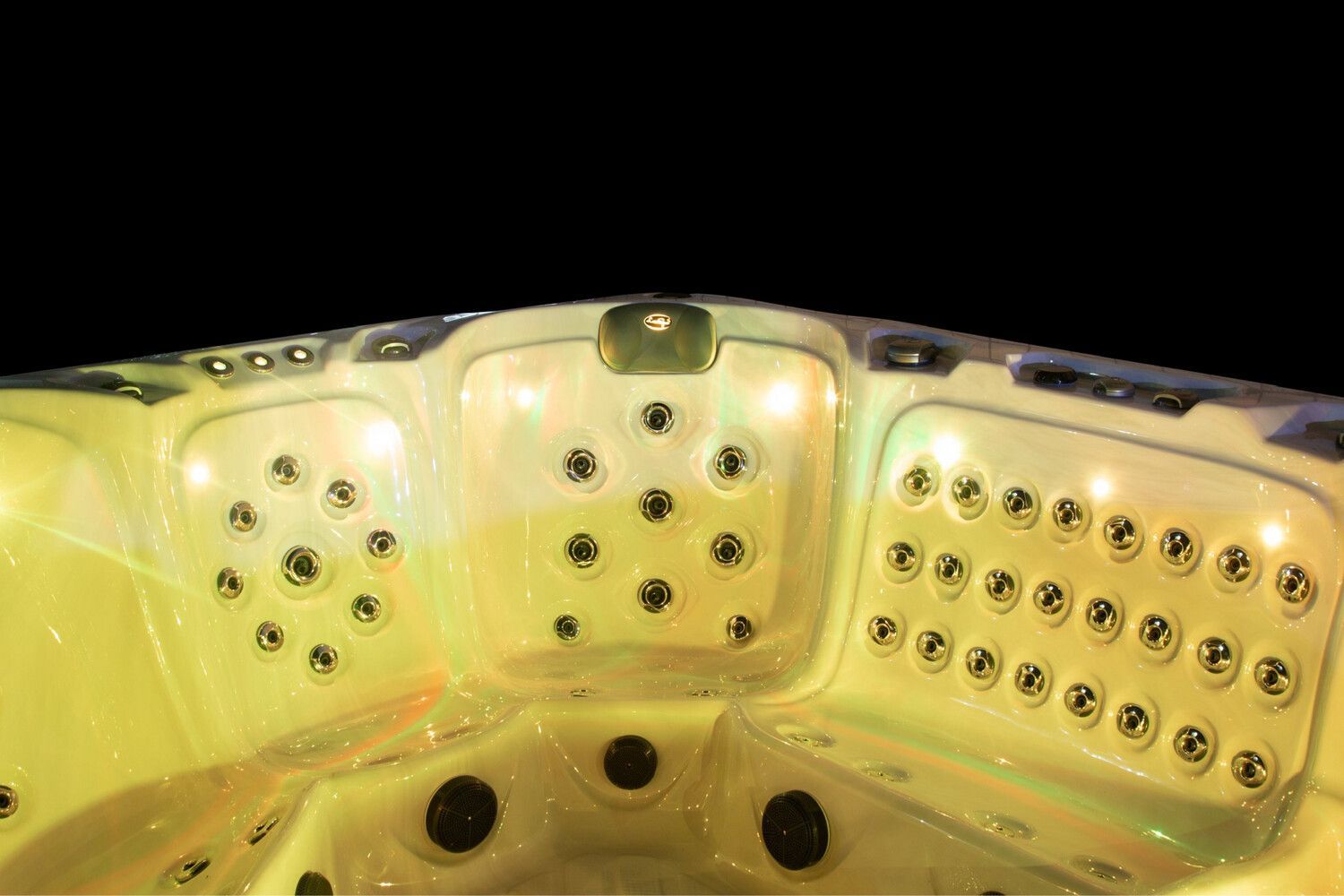 Hot tub interior with many jet nozzles, lit up with yellow light. Black background.