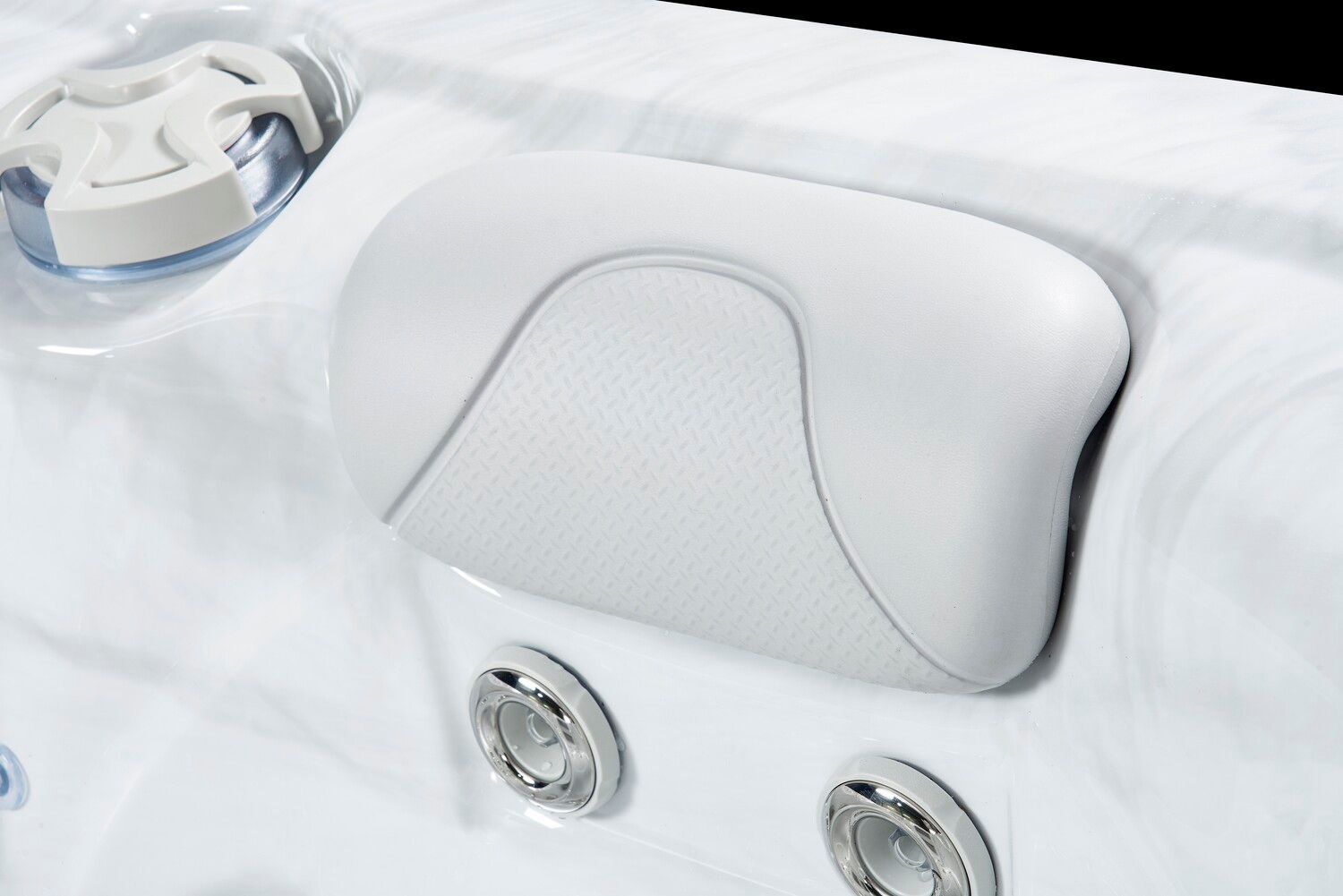 White spa pillow resting on the edge of a white hot tub, near water jets.