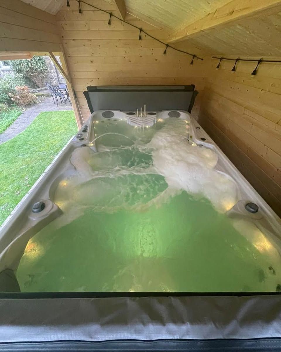 Hot tub in a wooden shelter with green water and jets.