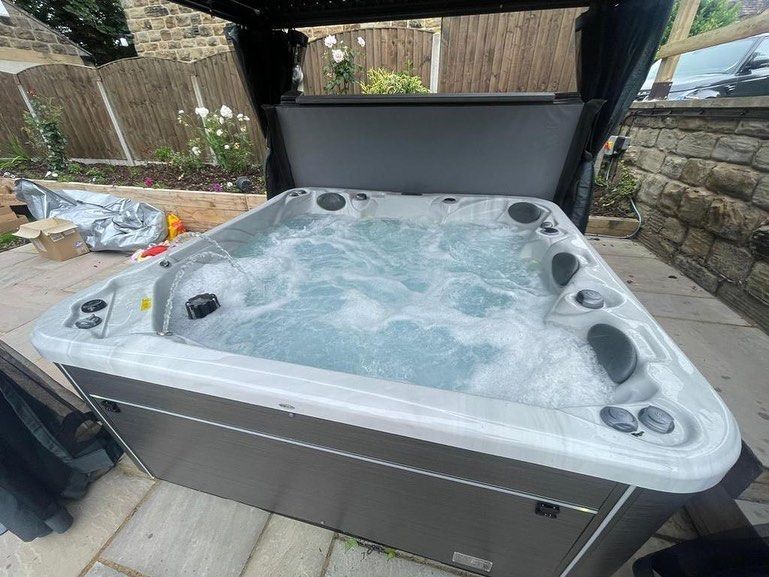 Hot tub with bubbling water, set on a patio, under a partial canopy.