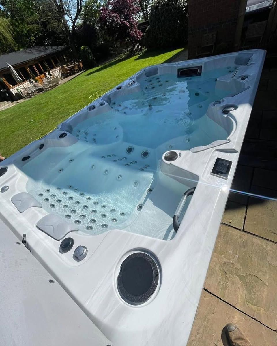 Swim spa filled with water, on patio near a green lawn.