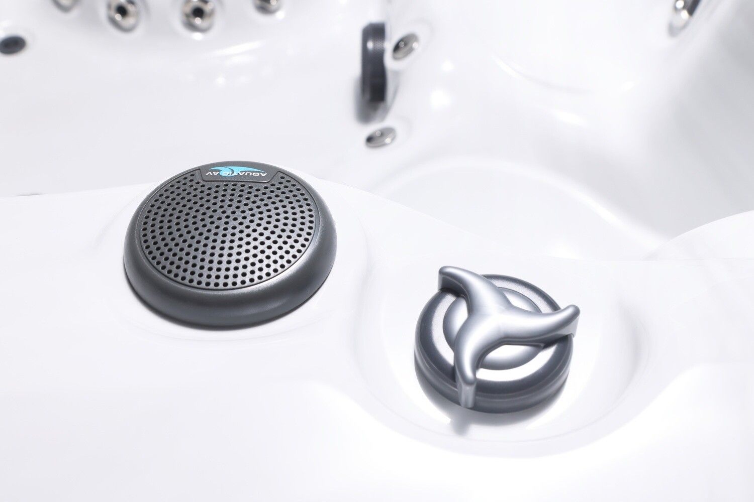 Close-up of a white hot tub interior with a speaker and a jet control knob.
