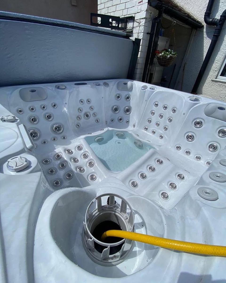 Hot tub with jets and a yellow hose filling it with water.