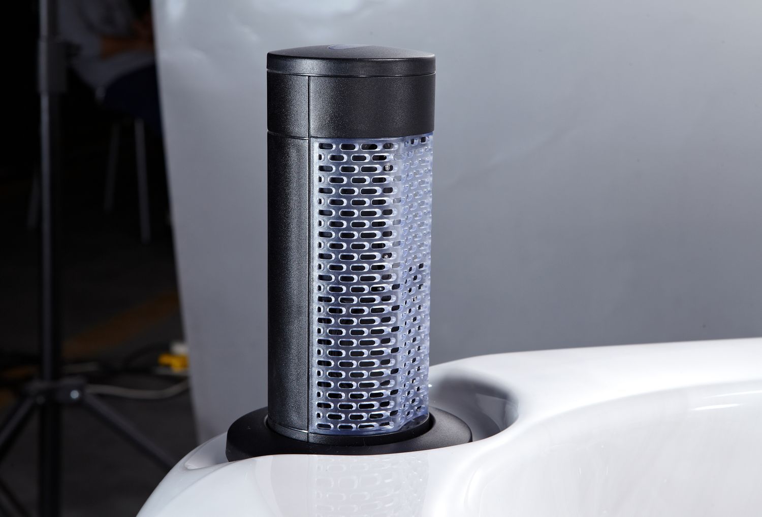 Black air purifier in a white container, possibly a hot tub.