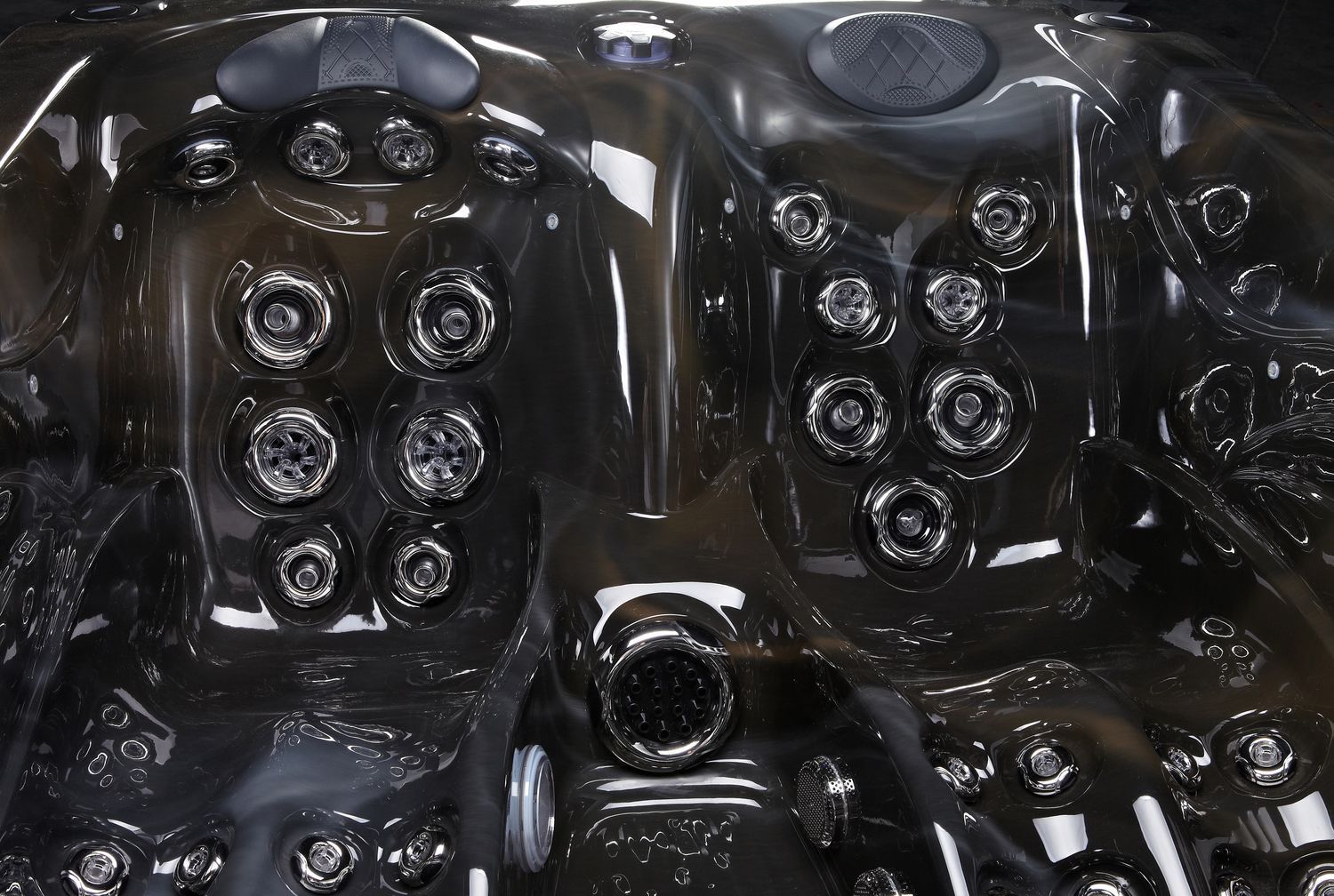 Close-up of a dark grey hot tub interior with numerous jet nozzles and molded seating areas.
