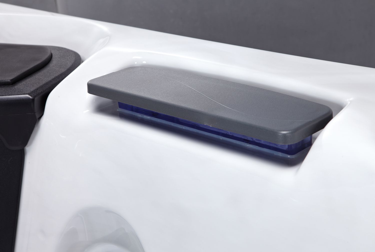 A close-up of a white hot tub with a rectangular, gray lid in the open position.