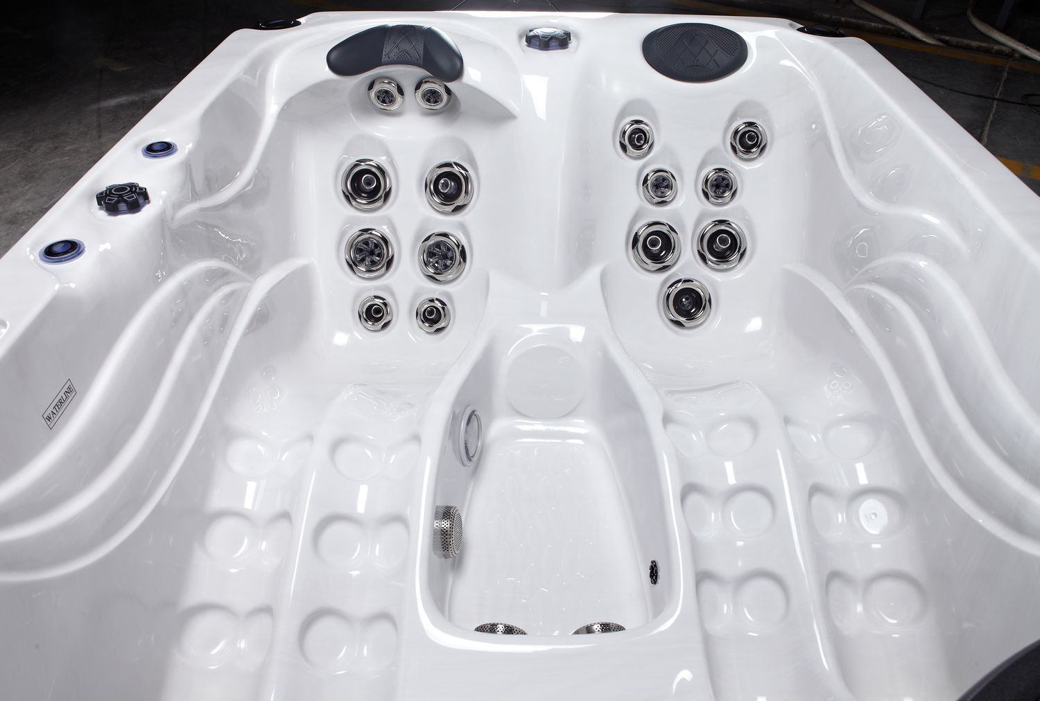 White hot tub interior with multiple jet nozzles and seating areas.