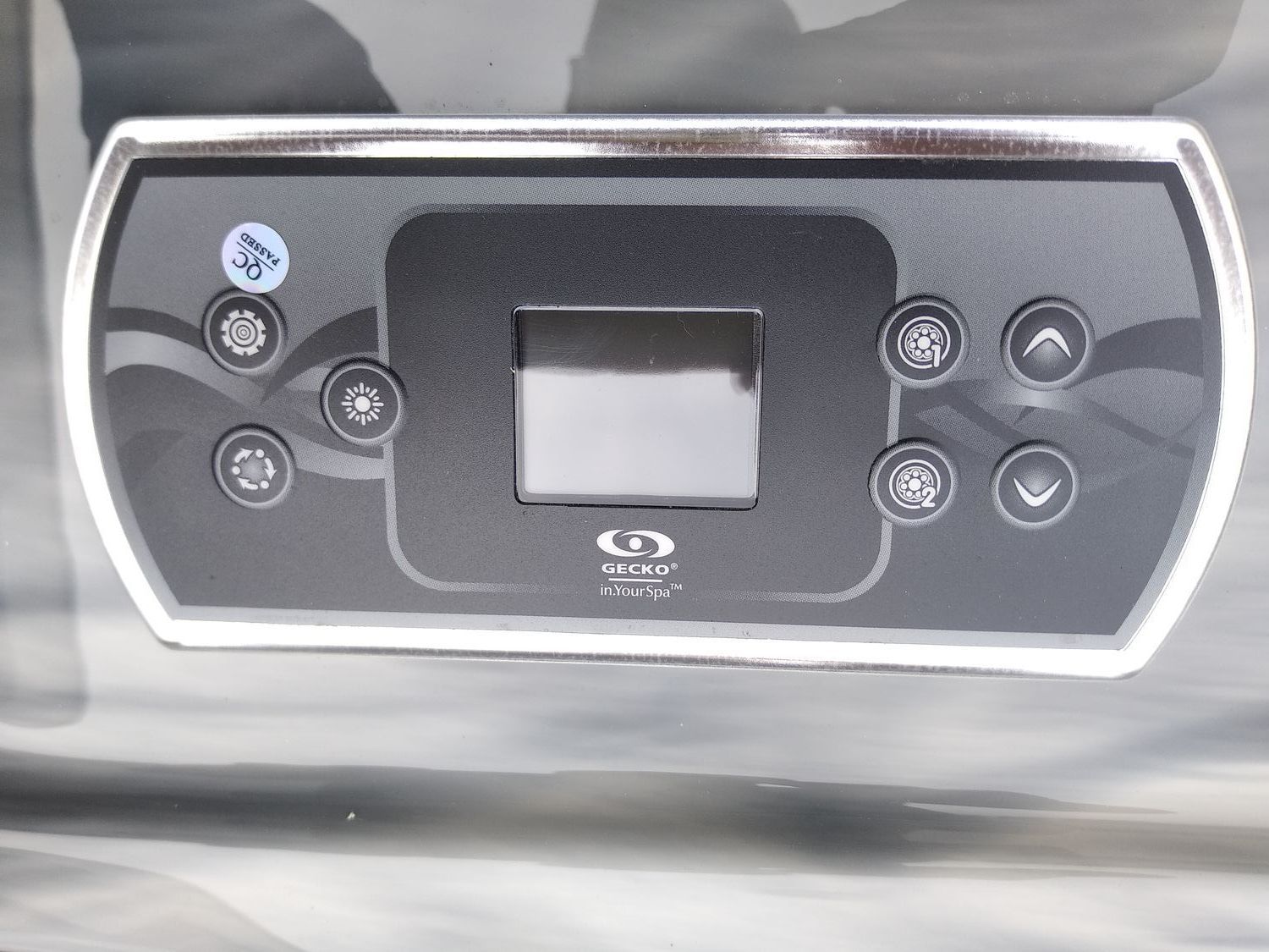 Black hot tub control panel with display, buttons, and silver trim.
