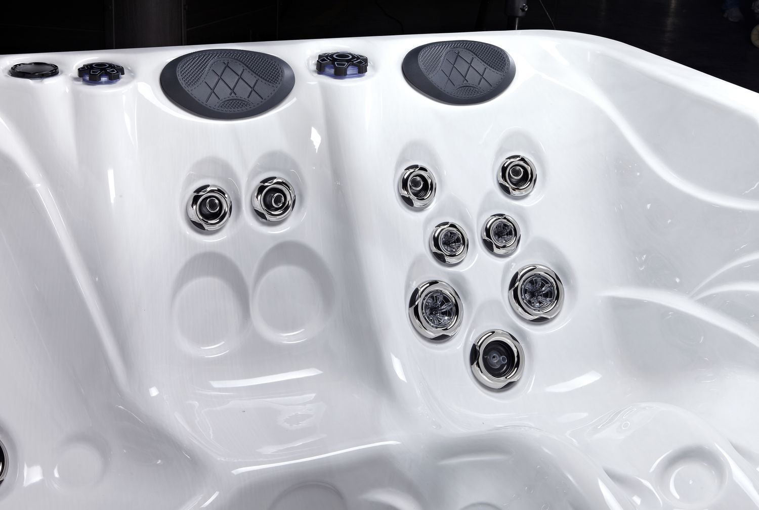 Close-up of a white hot tub interior, showing water jets, speaker covers, and molded seats.