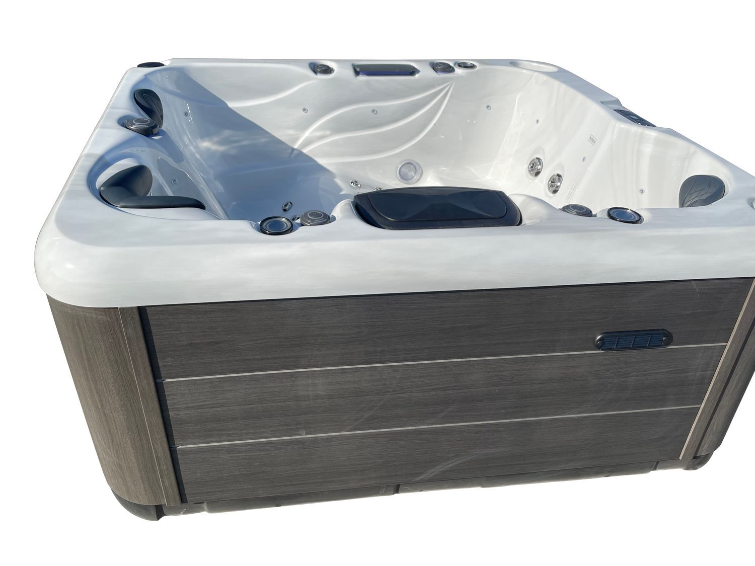 Hot tub with gray wood paneling and white interior, angled view.