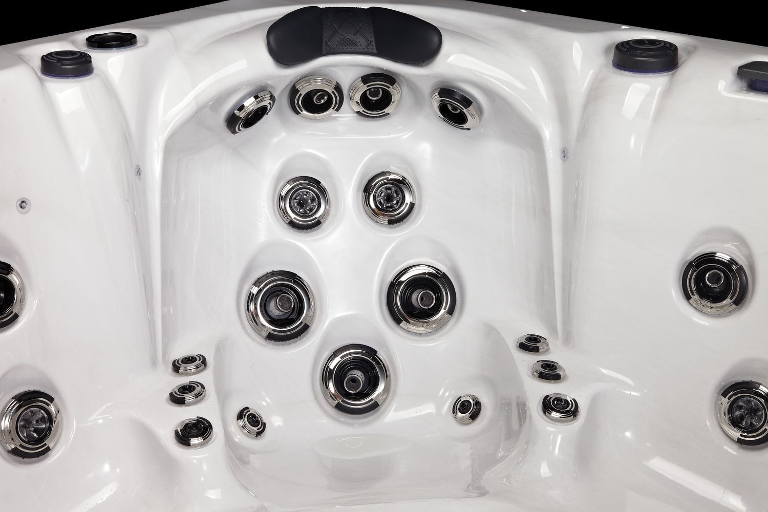 Close-up of a white hot tub interior featuring multiple silver jets and black headrest.