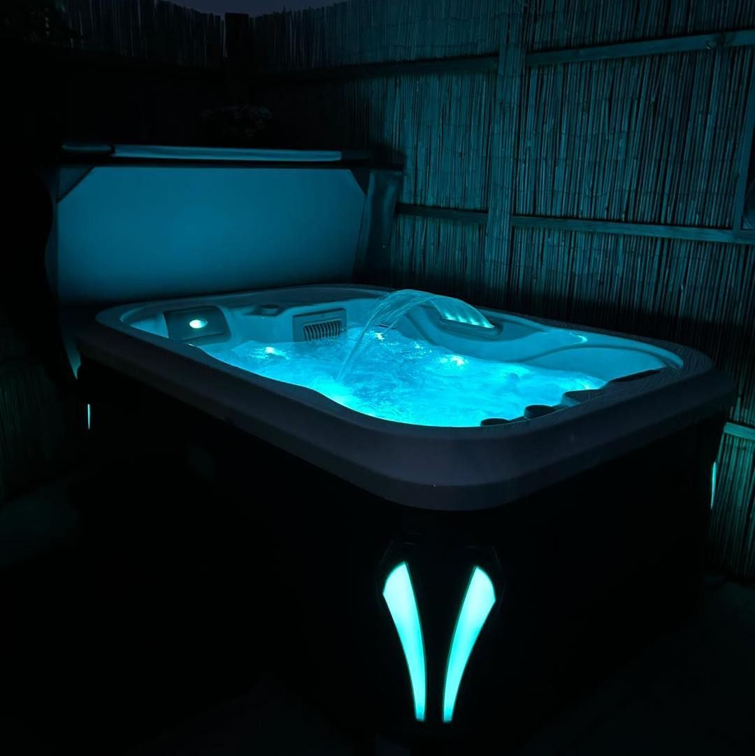 Lit blue hot tub at night with glowing accents.