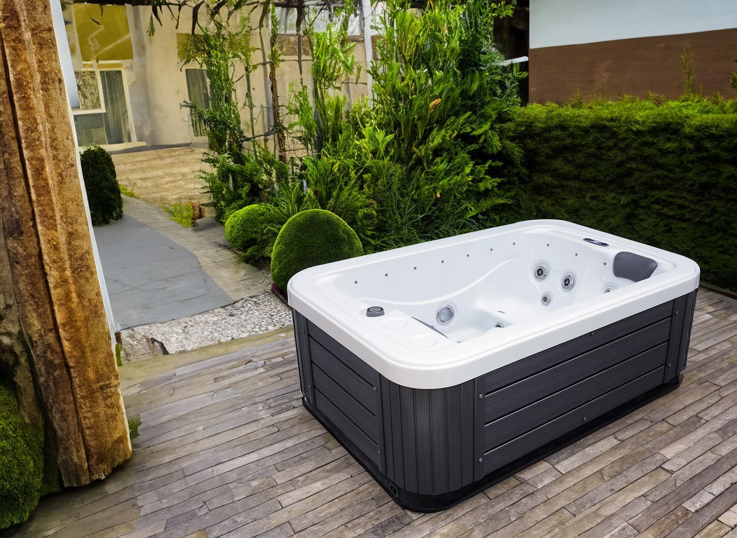Hot tub on a brick patio surrounded by greenery and a building in the background.