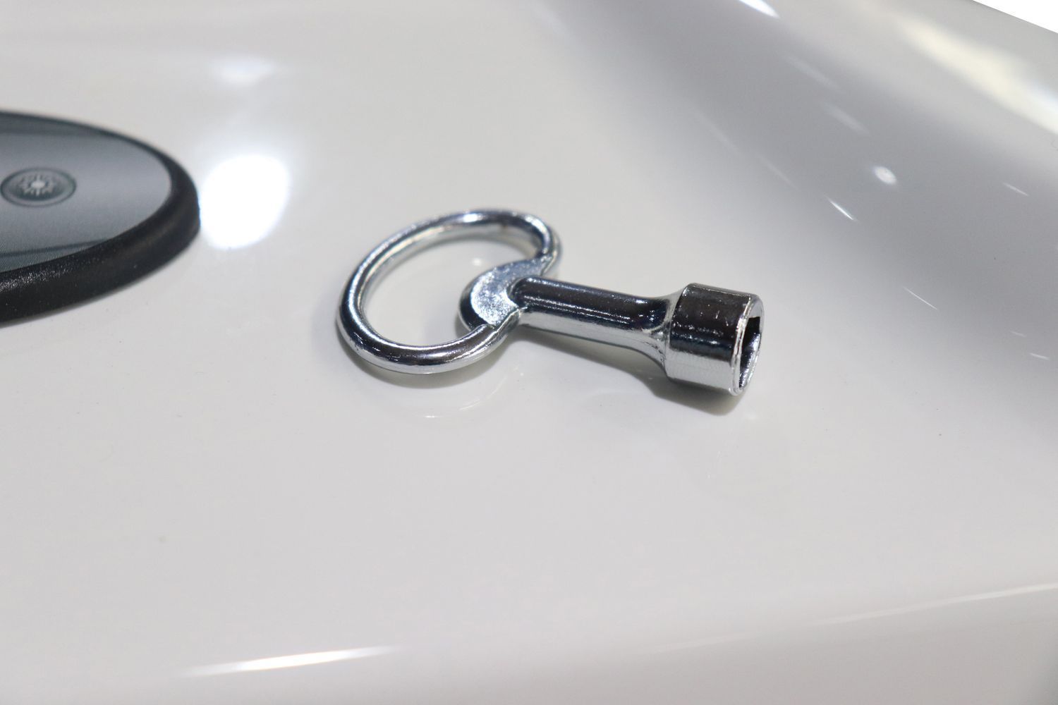 Shiny metal key with a loop handle, resting on a white surface.