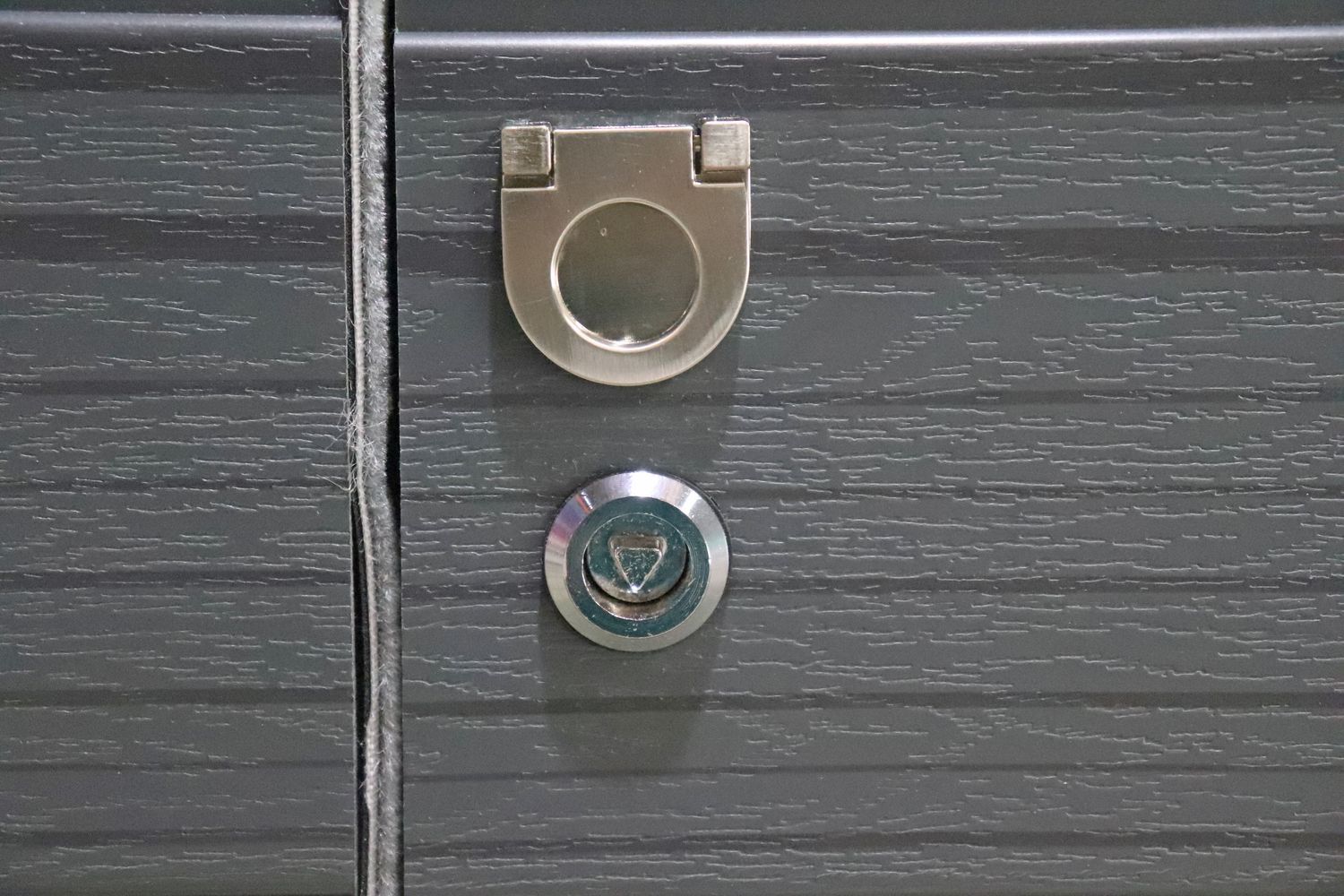 Close-up of a gray cabinet door with a silver handle and a key lock.