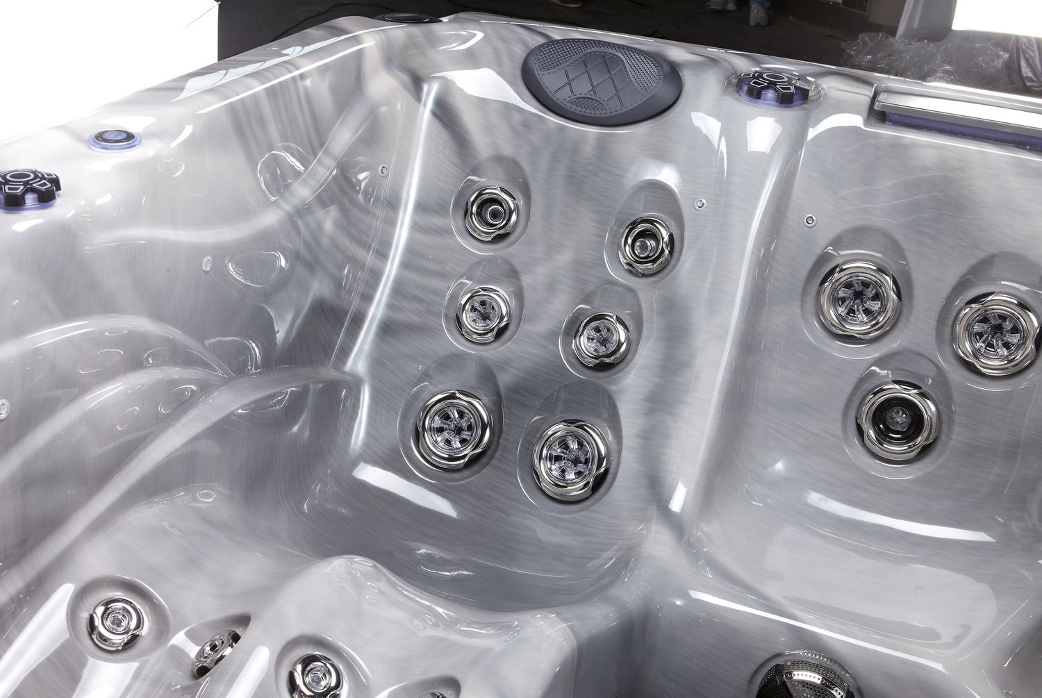 Close-up view of a gray hot tub interior with multiple water jets and a dark speaker.