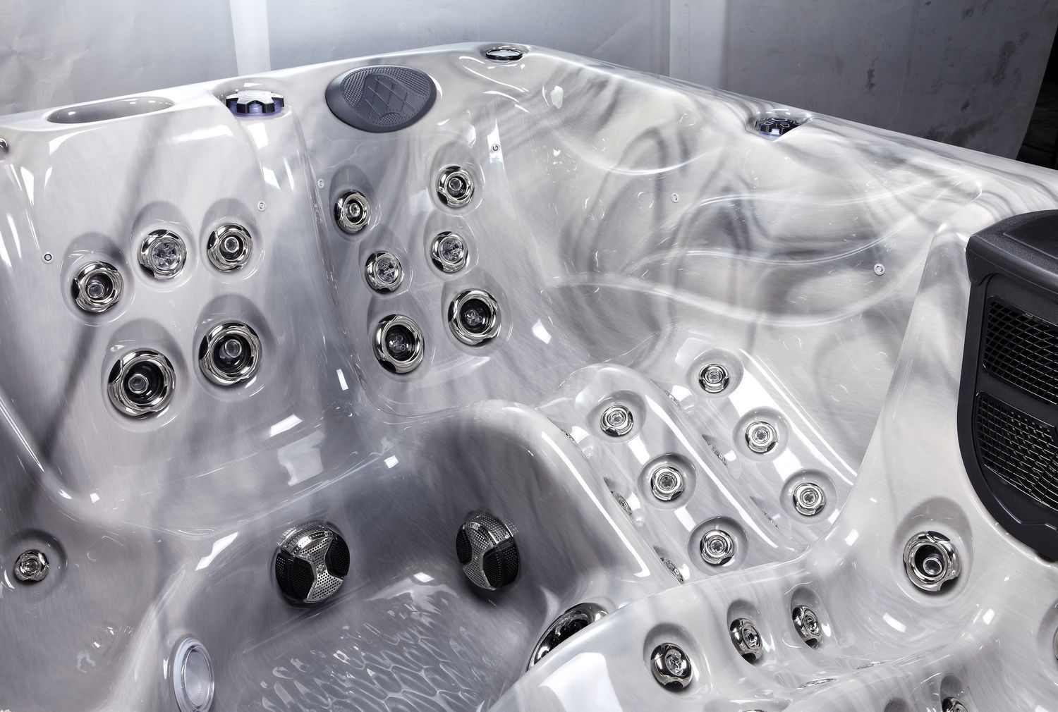 Close-up of a marbled, gray and white hot tub interior with multiple silver jets.