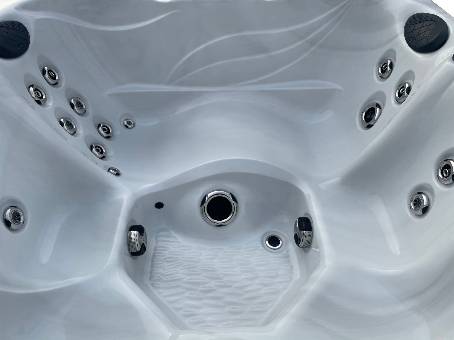 White hot tub interior with jets and a central drain.