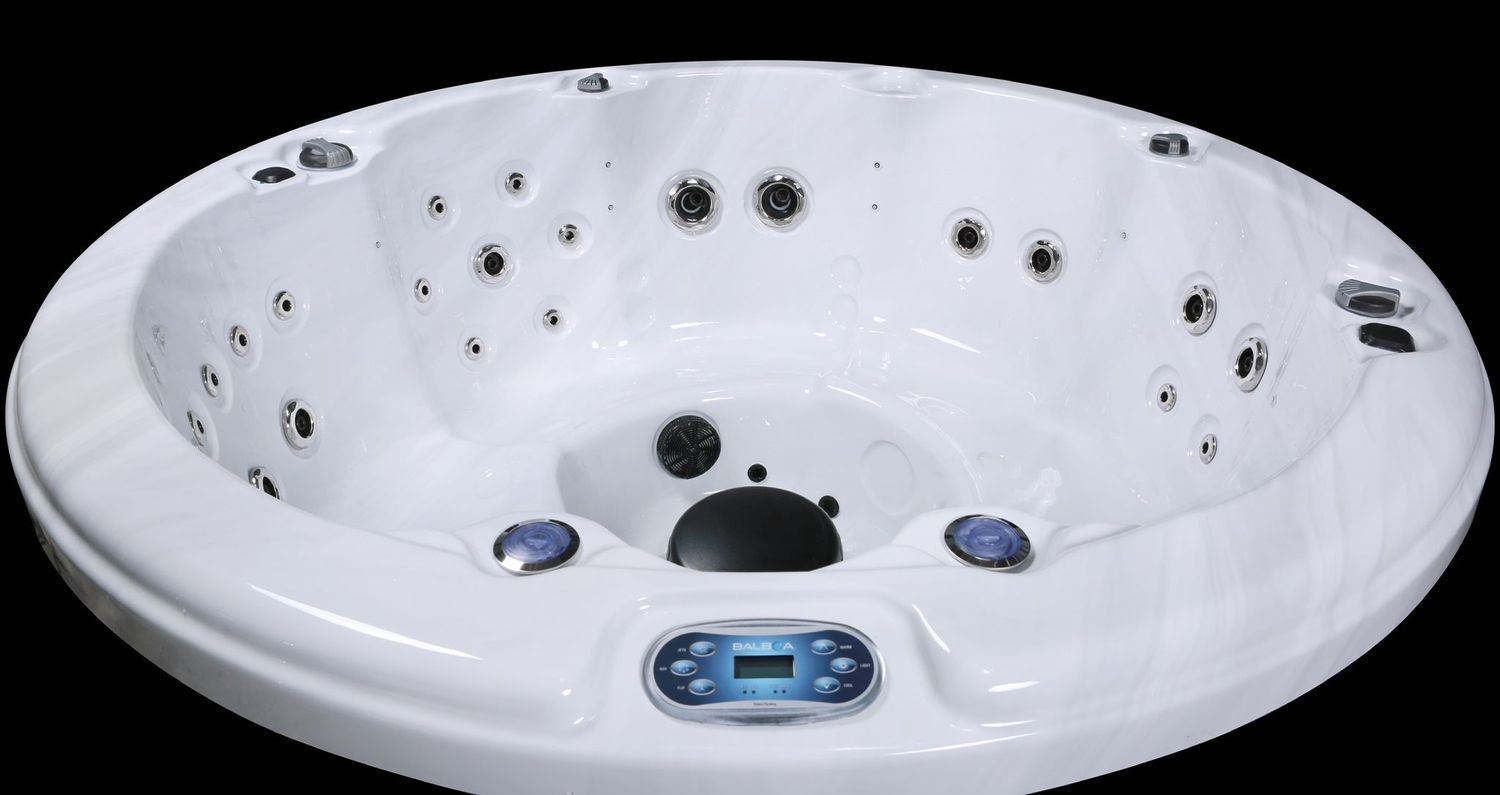 White, circular hot tub with numerous water jets and control panel.