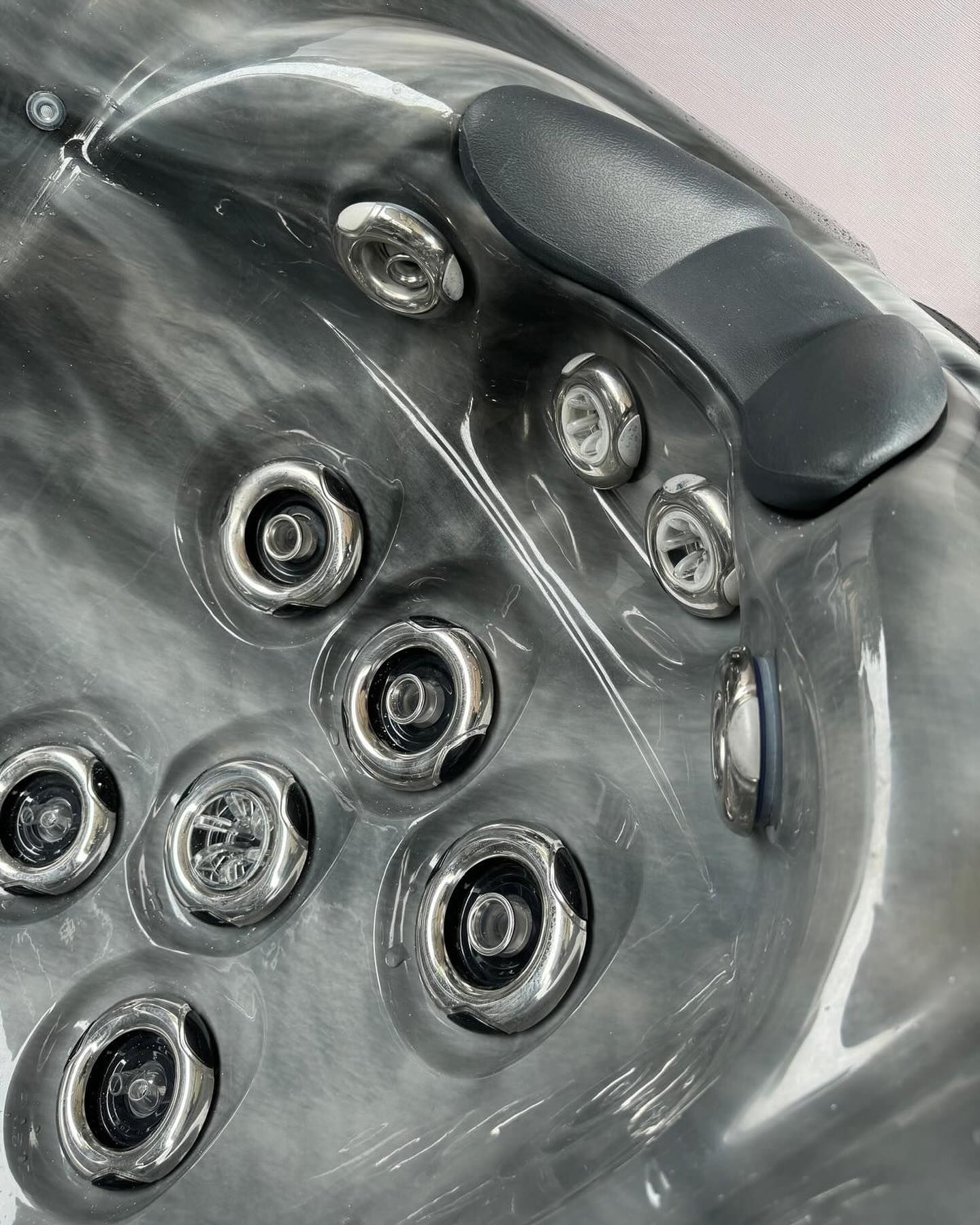 Close-up of a dark gray hot tub interior with several silver jets and a gray headrest.