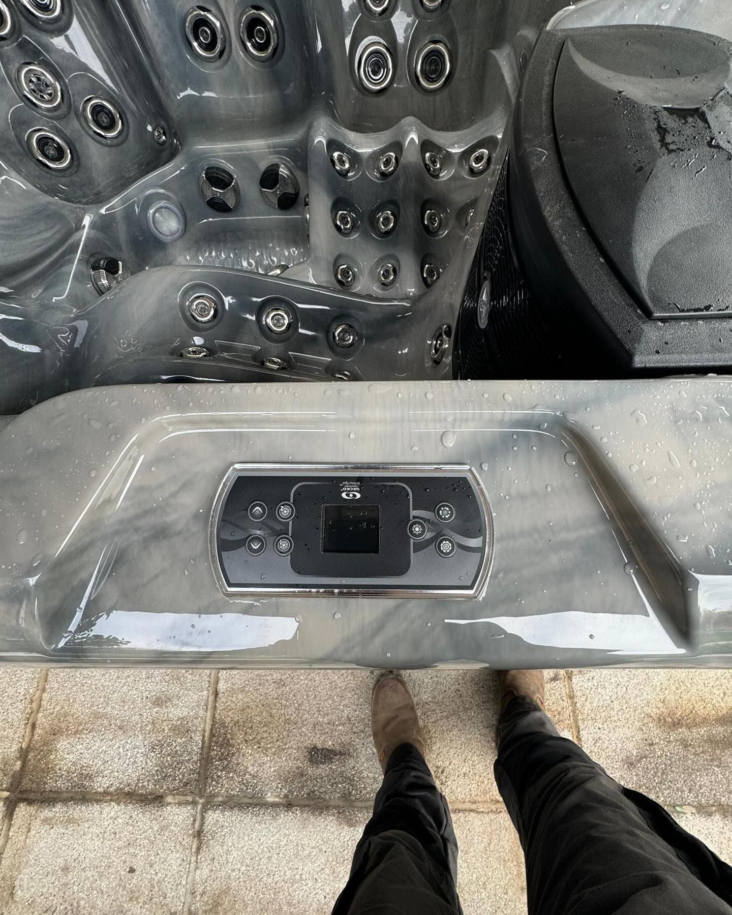 Hot tub control panel with jets. Gray and black. Person's feet visible.