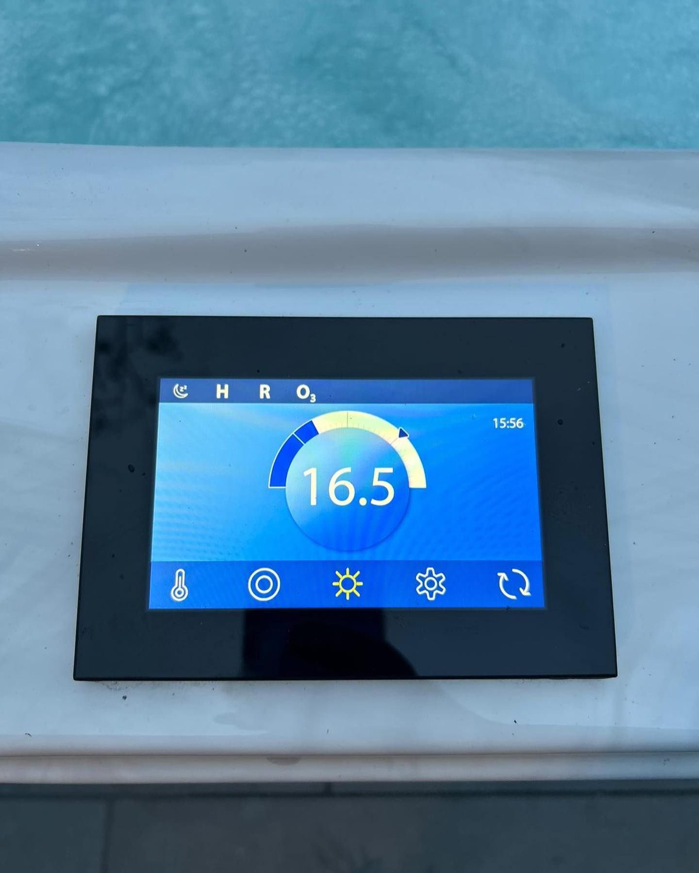 Black touch screen panel displaying pool water temperature of 16.5 degrees Celsius.
