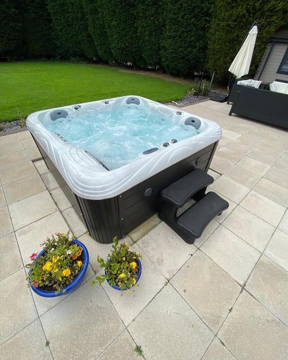 Hot tub bubbling on a patio, steps, flower pots, and outdoor seating visible.