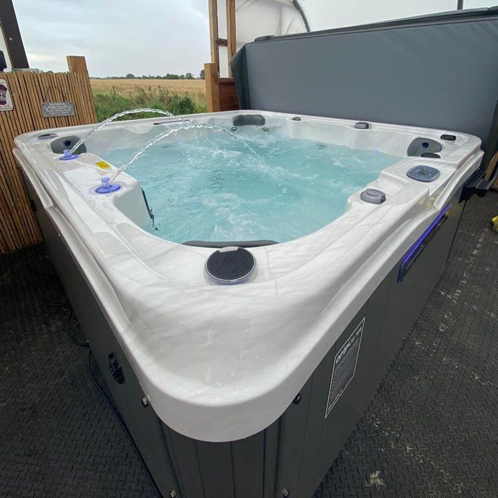 Triangular hot tub with water jets, set outdoors under a cloudy sky.
