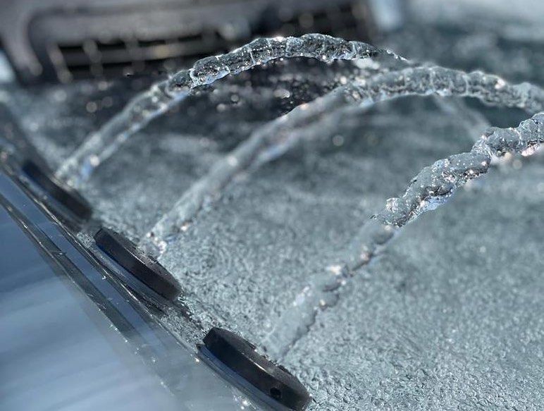 Close-up of water jets spraying into a pool or jacuzzi, creating clear, arching streams and ripples.