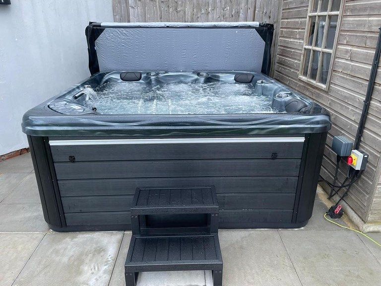 Hot tub with open cover, bubbling water, and gray steps.