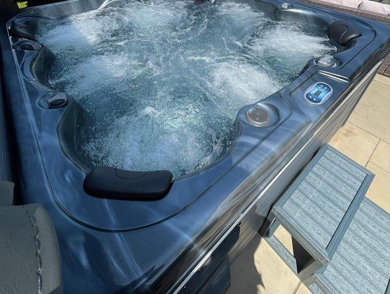 Hot tub with bubbling water, dark gray exterior, next to a small gray step.