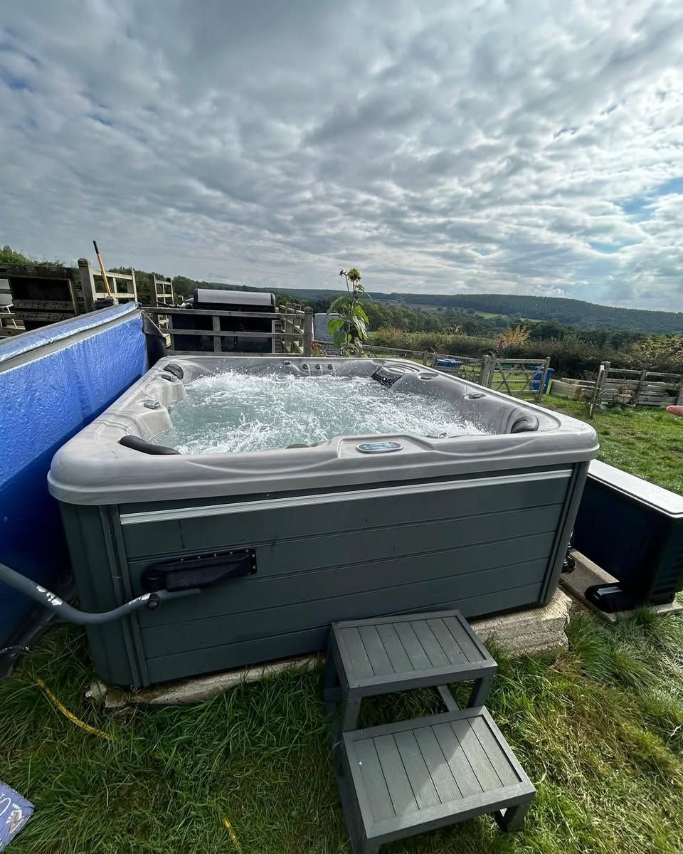 Hot tub outdoors, with bubbling water and grey paneling.