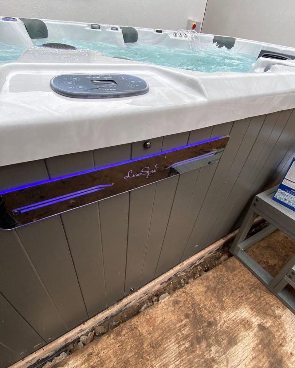 Hot tub with illuminated panel and control panel, water visible.
