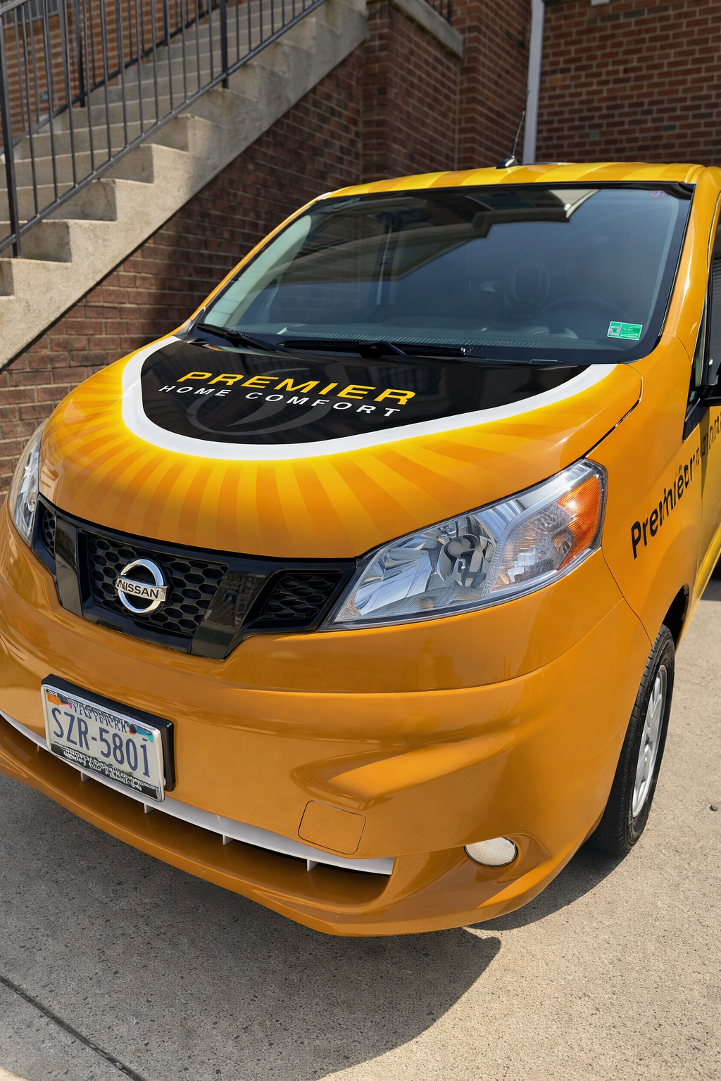 Orange Nissan taxi parked beside a brick stairway in daylight