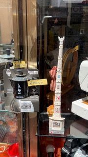 Vetrina con modellini in miniatura, tra cui una torre bianca e un oggetto nero e argento con cartellini del prezzo.