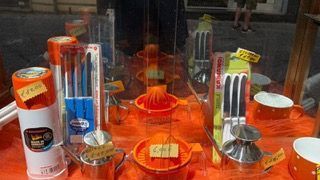 Un'esposizione di cosmetici e articoli da toeletta assortiti, di colore arancione brillante, su un bancone di un negozio.