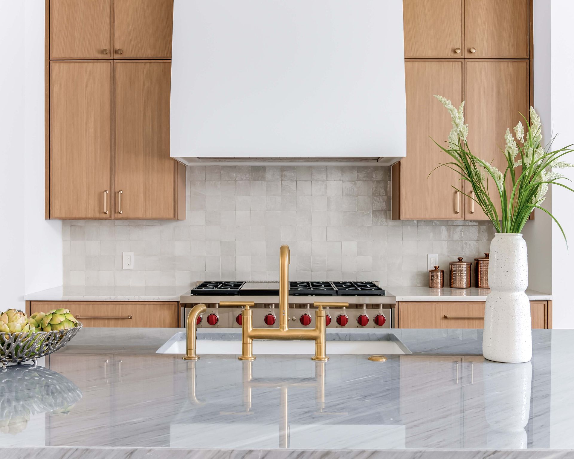 Modern kitchen with wood cabinets, gold faucet, and marble countertop.