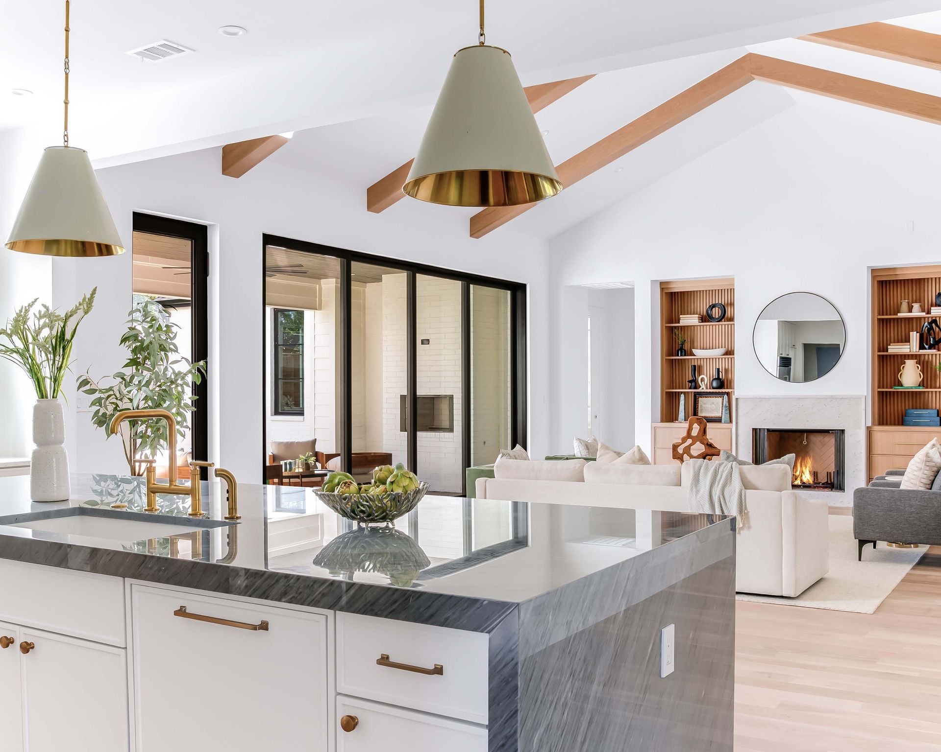 Modern kitchen with island, white cabinets, gold accents, and open concept to living area.
