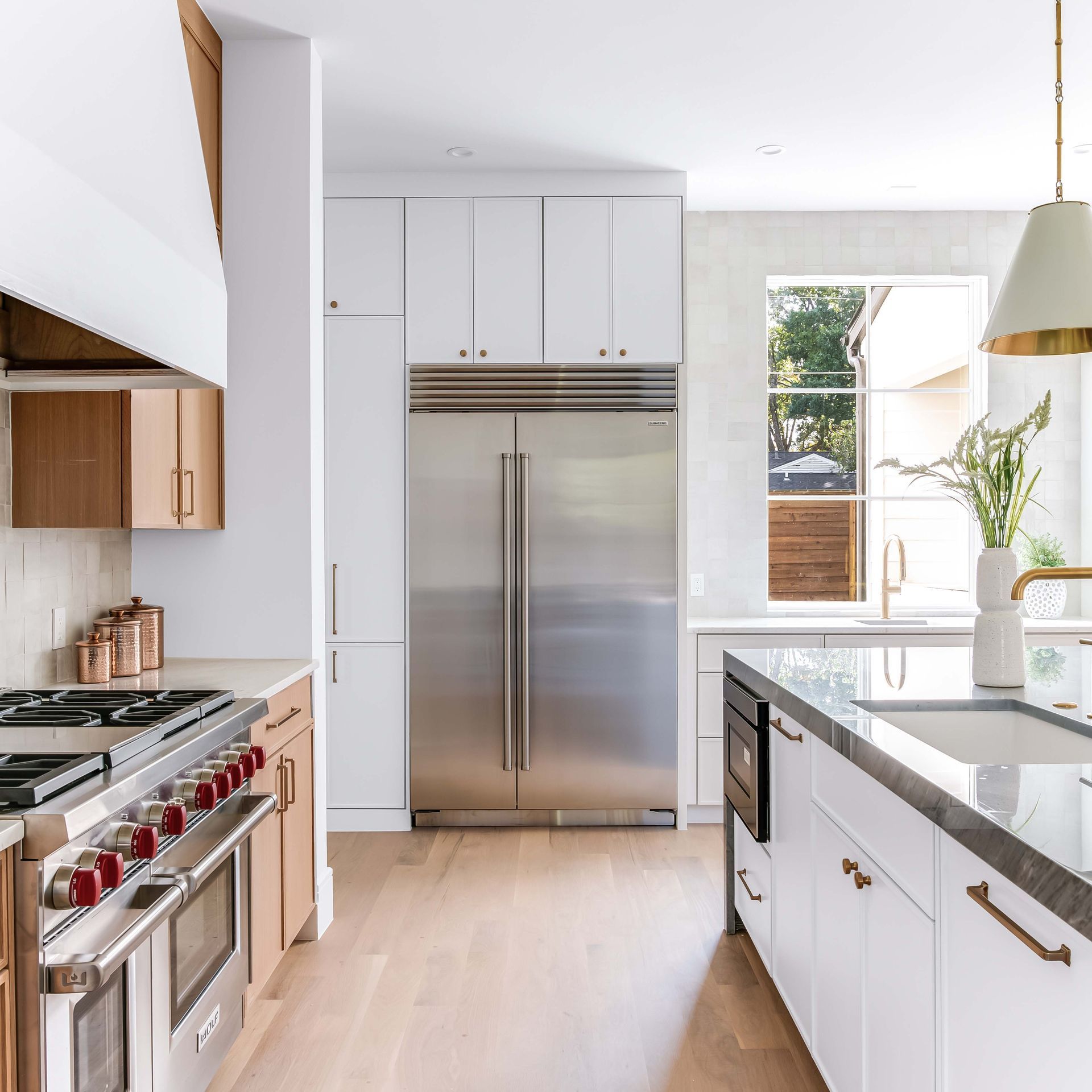 Modern kitchen with white cabinets, stainless steel refrigerator, and wood floors.