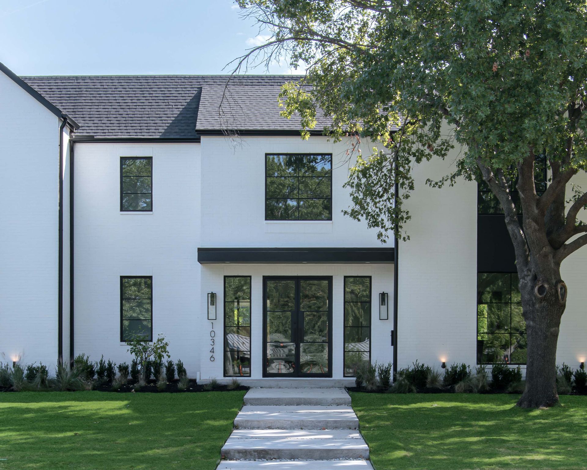 White modern house with black trim, windows, and door; a path leads to the entrance.