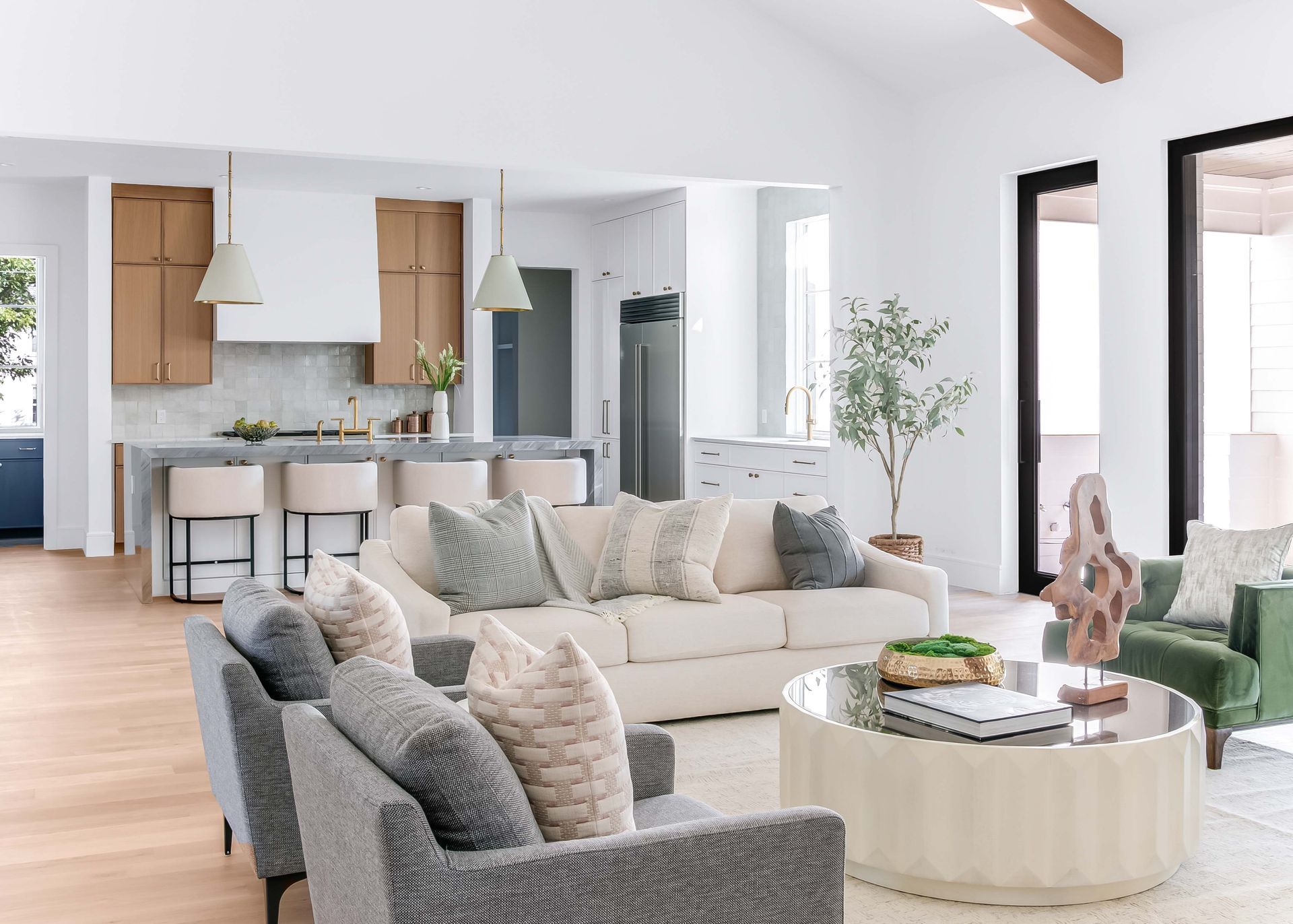Open-concept living space with kitchen, light-colored sofas, and a green armchair.