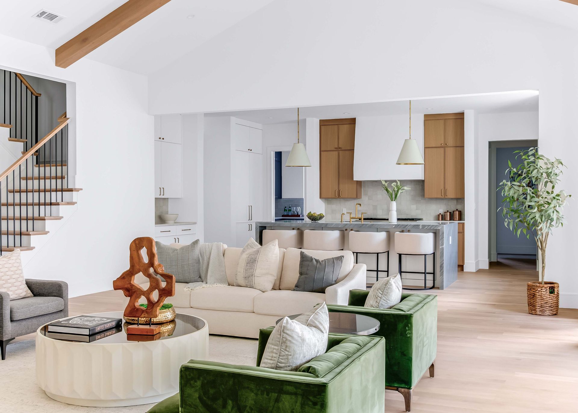 Open living space with white walls, wood floors, green and beige furniture, and a kitchen.
