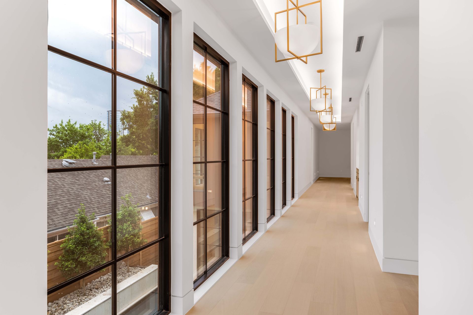 Long hallway with large windows and modern gold light fixtures.