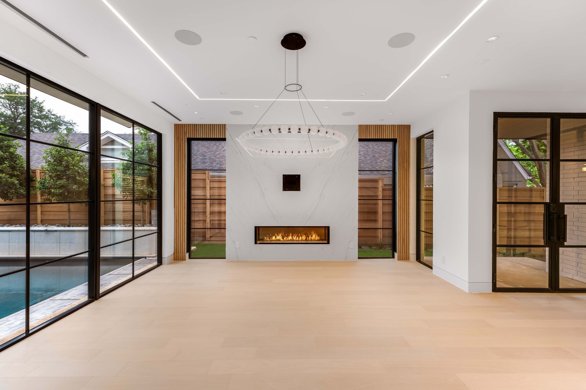 Modern living room with pool view, fireplace, and large windows.