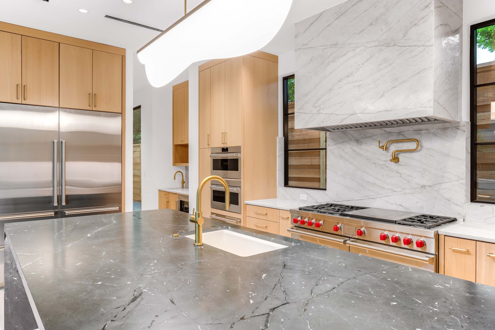 Modern kitchen with stainless steel appliances, marble accents, and a large island.