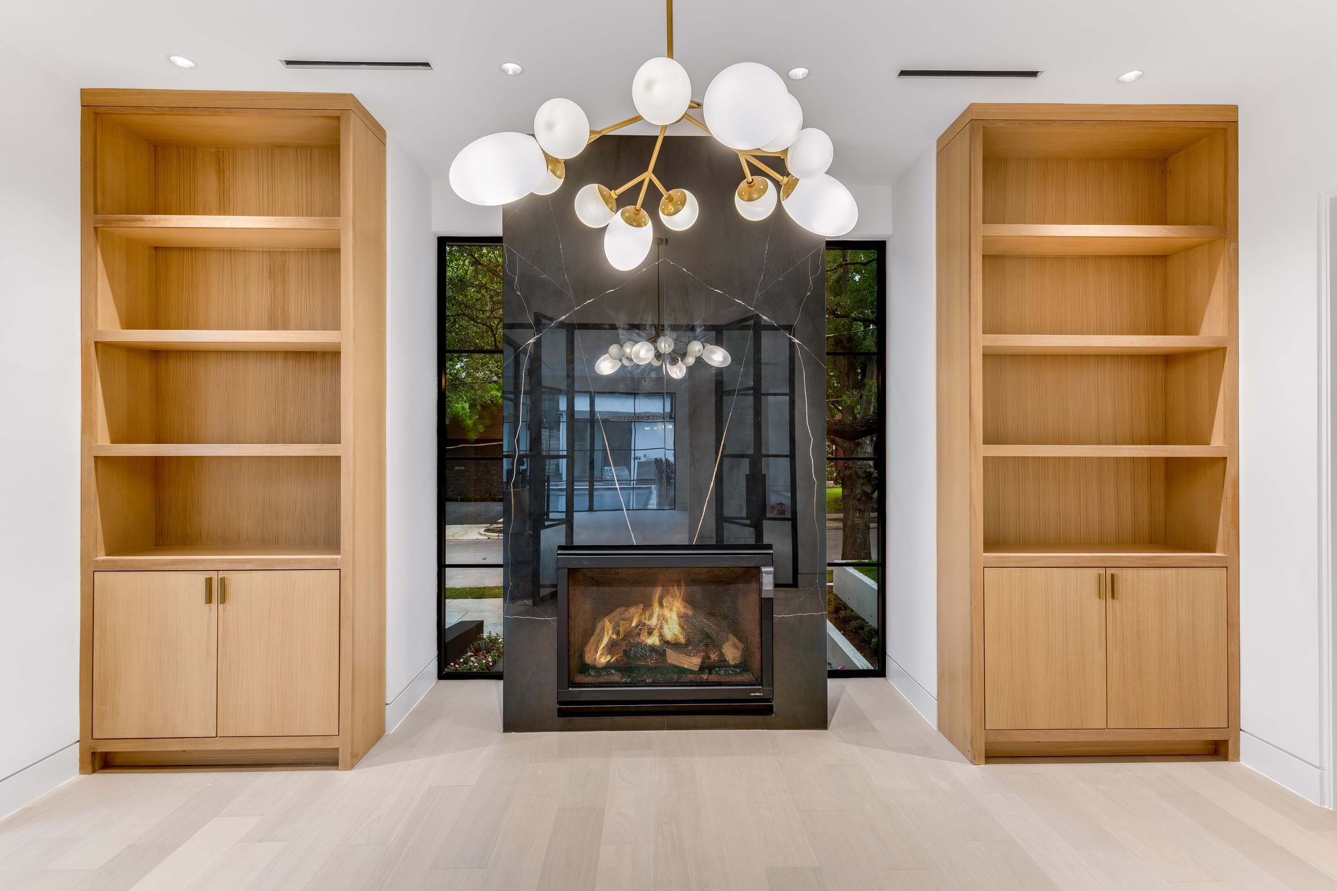 Living room with built-in bookshelves flanking a fireplace. Modern light fixture hangs above.