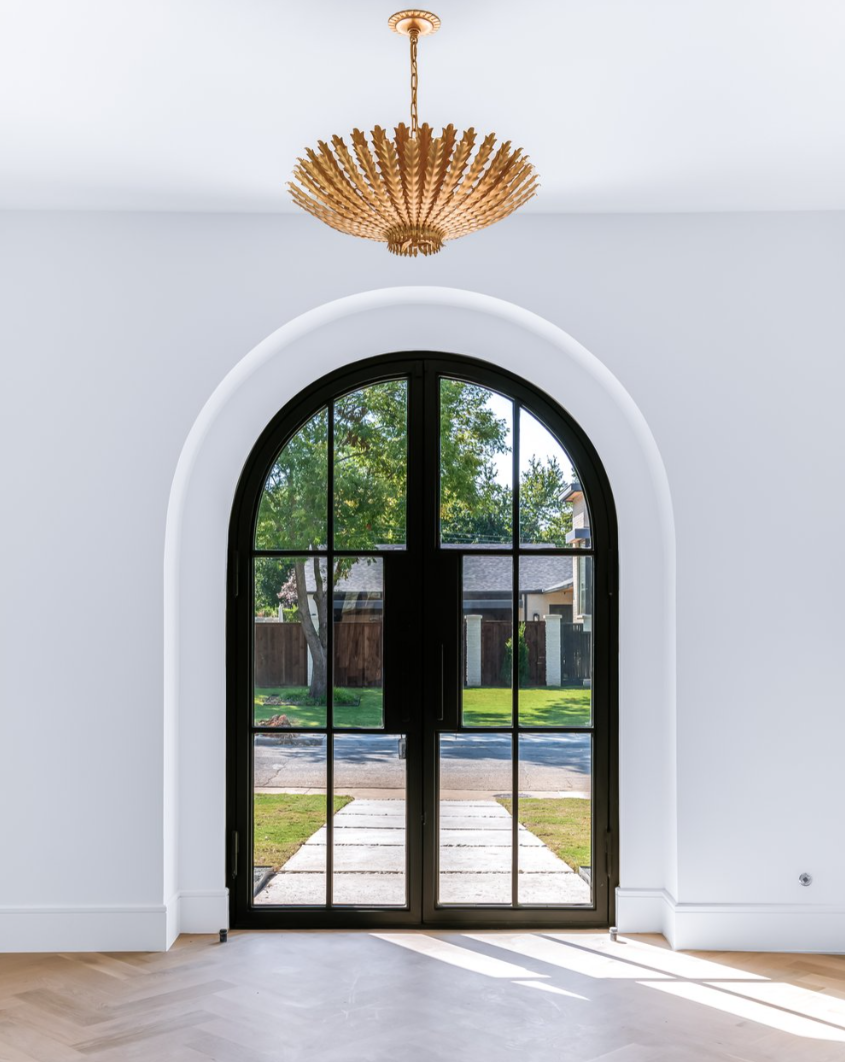 Black arched doorway with glass panels, white trim, gold chandelier.
