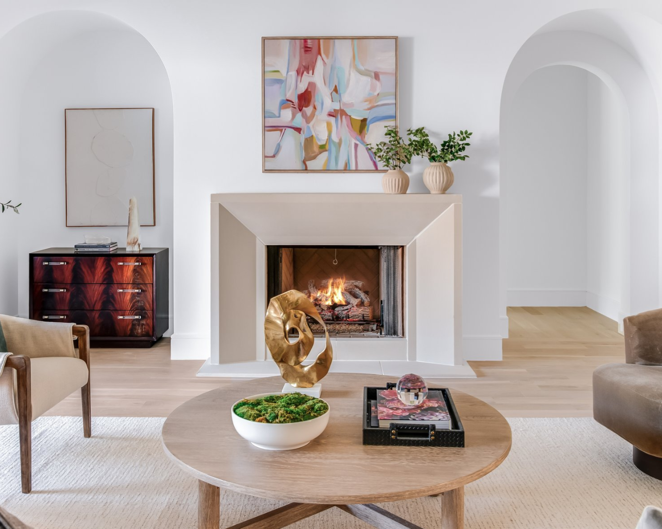 Cozy living room with fireplace, artwork, and round coffee table, showcasing a modern and elegant interior.
